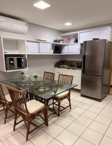 a kitchen with a glass table with chairs and a refrigerator at Marulhos Resort in Porto De Galinhas