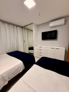 a hotel room with two beds and a tv at Marulhos Resort in Porto De Galinhas