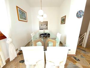 a dining room with a glass table and white chairs at White House in Cremia