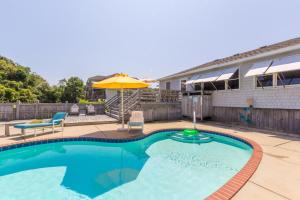 a swimming pool with an umbrella and a patio at 4601 - Sandy Bluff in Southern Shores