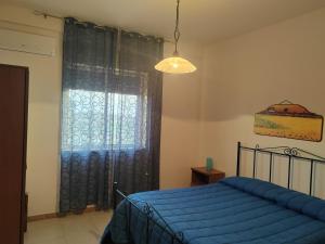 a bedroom with a blue bed and a window at Casa Mangiaracina in Porto Palo