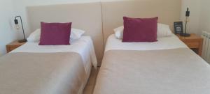 two beds with purple pillows in a room at Hostería Varvarco in Varvarco +9 photos