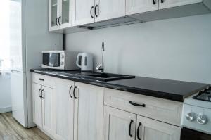 a kitchen with white cabinets and a sink and a microwave at Przystań Baseny in Nowogród Bobrzański