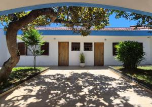 a white building with a tree in front of it at Aloogar Caragua Beach in Caraguatatuba