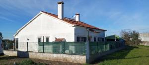 a white house with a fence in front of it at Quarto no Sótão in Coruche