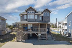 a house with a wrap around porch with a deck at 5469 - Below Deck OBX in Nags Head