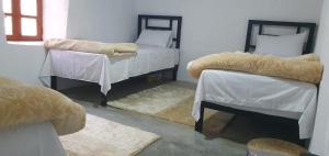 a room with two beds with white covers and rugs at Gîte OUHDOU in Midelt +14 photos