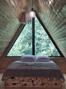 a bed in a room with a large window at vila pataraia in Martvili
