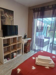 a living room with a tv and a bed with a red blanket at La Marceline Gîte avec piscine près de Lascaux IV in Aubas