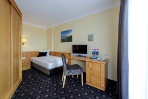 a hotel room with a bed and a desk with a computer at Hotel Zum Adler in Nidderau