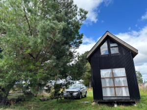 a black tiny house with a car parked in a field at Tiny House, Tiny Black Frutillar in Frutillar