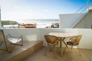 a table and chairs on a balcony with a view of the ocean at Praia das Maçãs Sea view Retreat in Colares