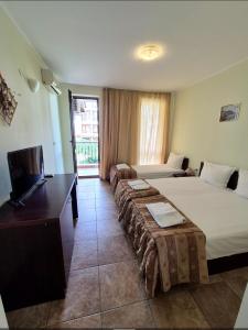 a hotel room with two beds and a flat screen tv at Family hotel Apolon in Nesebar