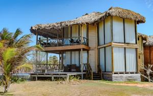a house on the beach with a thatched roof at BobZ Boutique Resort in Barra Grande