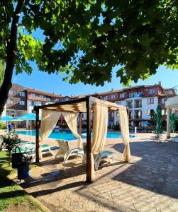 a gazebo with a canopy and chairs next to a pool at Family hotel Apolon in Nesebar