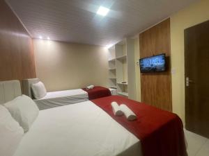 a hotel room with two beds and a flat screen tv at Pousada Corais de Pajuçara- MCZ in Maceió