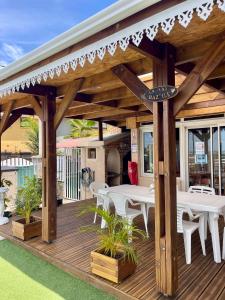 a wooden deck with white tables and tables at La Kaz Baz ' île in Étang-Salé