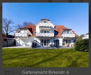 a large white house with a green lawn at Ferienwohnung Strand-Domizil Zingst in Niederdorla
