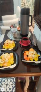 two trays of fruit on a table with a coffee mug at Hostal Casa de las Americas in Cartagena de Indias