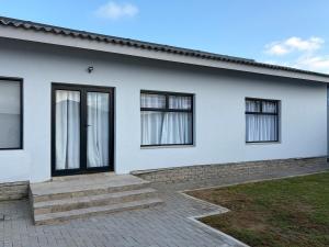 a white house with windows and a brick driveway at House Stillmar in Walvis Bay