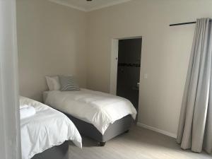 a bedroom with two beds and a door to a bathroom at House Stillmar in Walvis Bay