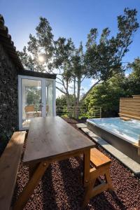 a wooden picnic table in a backyard with a swimming pool at Aldeia Dos Caldeirões in São Mateus