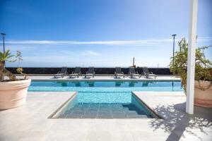 a swimming pool with chairs and the ocean in the background at Casa Conil Private 25m Heated Pool with Hydraulic Mobility Lift in Conil