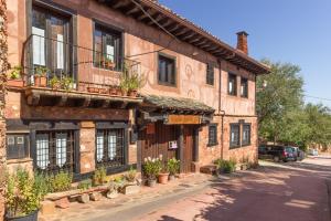 an old brick building with potted plants on a street at LA DEHESILLA in Madriguera