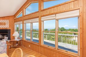 a living room with large windows and a fireplace at 3213 - Seaside Salvation in Duck