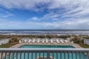 a swimming pool with chairs and the ocean in the background at 2869 - Seascape in Duck