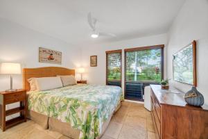 a bedroom with a bed and a desk and windows at Kahala 312 in Kipu +17 photos
