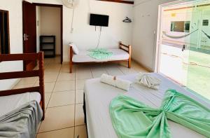 a bedroom with two beds and a chair and a window at PORTO SUÍTES PERUÍBE CHECK-OUT LIVRE aos DOMINGOS in Peruíbe