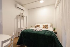 a bedroom with a bed with a green blanket at P&G Apto 202-San Gimignano in Caxias do Sul