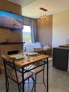 a dining room with a table and chairs and a kitchen at Pousada Varandas de Minas in Monte Verde