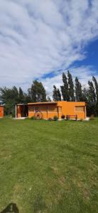 a house in a grassy field with a bench at Cabañas Rincon de Campo San Andres De Las Sierras in Villa Ventana