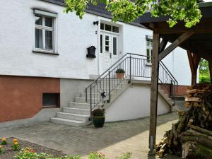 a white house with a white door and stairs at Bright apartment in the Sauerland with conservatory large terrace and awning in Assinghausen