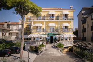 a yellow building with white balconies on a street at Hotel Le Lampare in Caorle