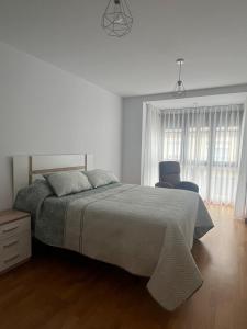 a white bedroom with a bed and a chair at El rincon del Cares in Panes
