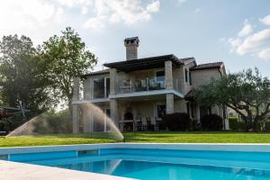 a house with a swimming pool in front of a house at Apartments Villa Sotlar with pool in Umag
