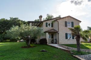a house with a lawn and trees in front of it at Apartments Villa Sotlar with pool in Umag