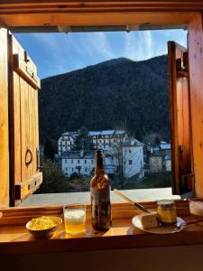 a bottle of beer sitting on a table in front of a window at La mansarda in Santa Maria Maggiore