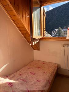 a small room with a bed and a window at La mansarda in Santa Maria Maggiore