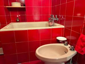 a red bathroom with a toilet and a bath tub at La mansarda in Santa Maria Maggiore