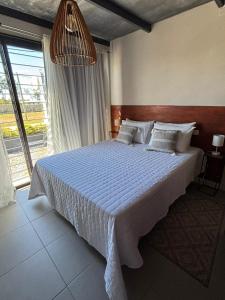 a bedroom with a large bed with a large window at Apart Las Tunas Carmelo in Carmelo