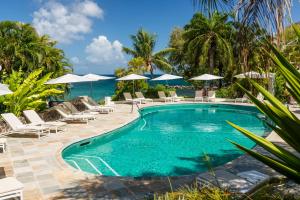 a swimming pool with chairs and umbrellas and the ocean at BodyHoliday St Lucia - All Inclusive in Gros Islet