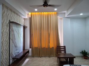 a living room with an orange curtain and a television at The Rustic Inn Kaziranga in Kāziranga