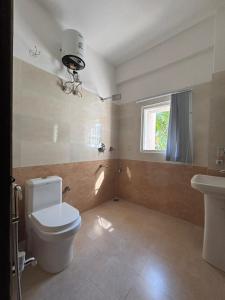 a bathroom with a toilet and a sink and a window at The Rustic Inn Kaziranga in Kāziranga