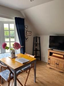 a living room with a table and a television at The Bird Loft Studio in Horsted Keynes