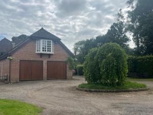 a brick house with a garage with a window at The Bird Loft Studio in Horsted Keynes