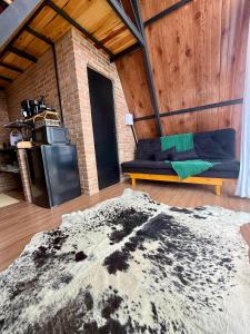 a living room with a couch and a brick wall at Cabana do sol Chalés Vero Verde in Serra Negra +25 photos
